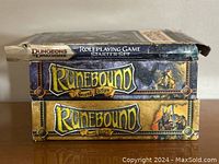 Photo showing three boxed games stacked: Dungeons & Dragons Roleplaying Game Starter Set on top, two Runebound Second Edition boxes below. The D&D box shows wear and damage to edges.