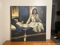 Full view of canvas painting of two women on furniture, face details blurred, mainly dark background with highlights.