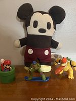 Photo showing the Disney plush Mickey Mouse and three Nintendo McDonald's toys: Mario in pipe, Turtle on snowboard, Bowser breathing fire.