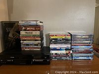 Photo showing Toshiba DVD/VCR combo player with stacks of DVDs beside it.