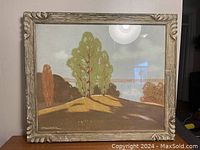 Full view of the landscape painting showing trees on a hill and the ornate carved wood frame.