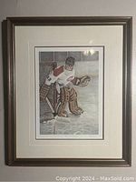 Framed full view of the print showing the hockey goalie in front of the goal net on ice, with white mat and brown frame.