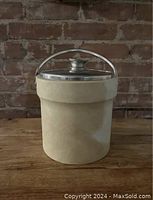 Front view of the beige Kraftware ice bucket with silver lid and handle, showing overall condition and design.