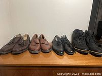 Four pairs of men's shoes, varying styles including brown leather dress shoes, black dress shoes, and black boots, all size 10.5, shown on wooden surface.