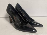 Side-angle view showing the black patent leather finish and overall shoe shape.