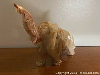 Side view of onyx elephant figure showing trunk raised and natural stone banding.