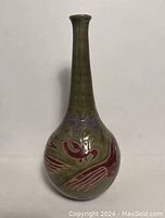 Front view showing the long neck and rounded base with red bird design on green background.