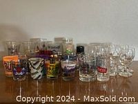 Wide view of a large collection of shot glasses with various designs on a flat surface, showing condition and diversity.