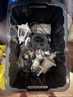 Plastic bin containing multiple wall sconces with attached wiring viewed from above.