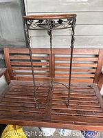 Full view of the oval wicker top and metal legs with twirled decorative metalwork and leaf motifs on the sides.