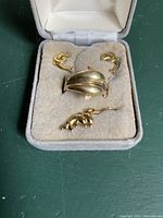 Photo showing the 10k gold dolphin ring, earrings, and pendant inside a grey velvet jewelry box.