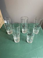 Group photo of five clear vintage glasses standing on a flat surface, showing overall condition and relative size.