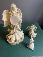 Front view of large and two smaller angel figurines and small angel ornament