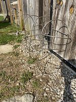 Two stainless steel boat fender holders mounted on a fence showing wire frame structure and bent joint.