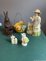 Full view of Easter lot including chocolate bunny planter, yellow chick flower pot, gardening lady figurine, bunny kid figurine, cake lady figurine and small lady figurine.