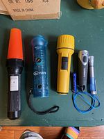 Lot overview showing six flashlights of varied sizes and colors arranged on a table for condition and detail assessment.