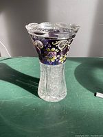 Clear cut crystal vase with a purple top section decorated with handpainted floral patterns and scalloped rim.