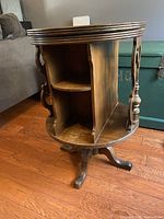 Wooden revolving table with multi-legged pedestal base and scrollwork sides, showing condition and structure