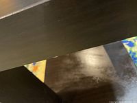 Close up image showing dark wood finish and minor scratches or wear marks on the table surface