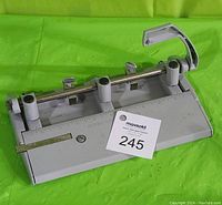Front view of ACCO-MUTUAL 400 three hole punch showing lever, hole guides, ruler, and base.