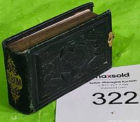 Black tooled leather miniature photo album with gilt edges and metal clasp