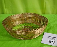 Front angled view of round brass wire basket showing woven construction and curved rim