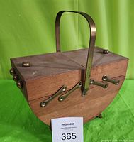 Photo of brass and wood cantilever sewing basket closed, showing brass handle and hardware, two brass knobs on lids (one missing).