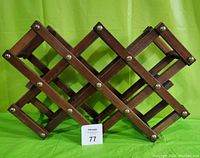 Front view of the expanded wooden bottle rack showing lattice structure and metal rivets.