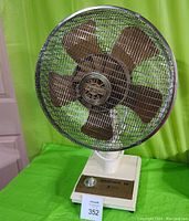 Full front view of the Torcan electric fan showing metal blades inside a protective grill with a beige/cream stand.
