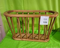 Front angled view of wooden magazine rack showing open slat design and natural wood finish.