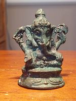 Front view of the small antique bronze Ganesha statue showing the deity seated with an elephant head and detailed base.