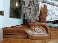 Side profile of the large wood carved wolf head sculpture showing detailed eye and snout with articulated lower jaw.