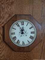 Front view of the Rensie octagonal wood framed wall clock showing the Roman numeral dial and decorative center design.