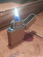 Lighter open, flame lit showing adjustable windscreen and flint wheel