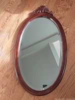 Wooden oval mirror front view showing carved top detail and condition of the mirror surface reflecting ceiling.
