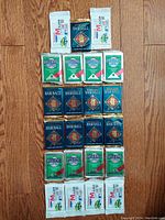 Top-down view of all 23 sealed packs arranged on hardwood floor