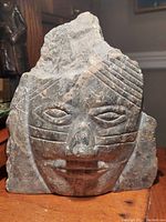 Front view of the Inuit granite facial sculpture showing stylized carved facial features and engraved markings.