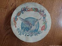Top view of the round hand drum showing the full hand painted swan design with colorful Celtic-style border on the drumhead.