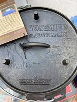 Close-up of black cast iron Dutch Oven lid with Yosemite National Park design and Camp Chef branding, showing surface details and product tag.