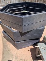 Three stacked black plastic raised garden beds with hexagonal shape.