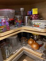 Corner cupboard shelves packed with various glass and plastic food storage containers, jars, and a metal canister
