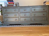 Full frontal view showing the dresser with multiple drawers and distressed blue-green paint with rust accents.