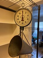 Photo showing full hanging scale with metal cone basket and dial face with hanging hook on top.