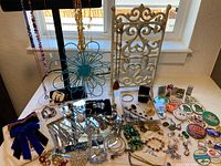 Wide view showing arrangement of assorted jewelry, enamel pins, lighters, display stands, and a mirror on table near window.