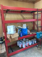 Full view of assembled red steel shelving rack in garage with items on shelves