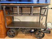 Front view of the rolling cart showing wood top, metal frame, wire baskets, and bottom shelf.