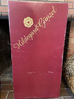 Closed red display box with gold Hildegard Gunzel logo and flower.