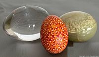 Three decorative eggs shown: clear glass, hand-painted geometric, and stone with moss