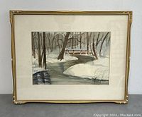 Framed painting featuring a winter scene with a stream and trees in snow.
