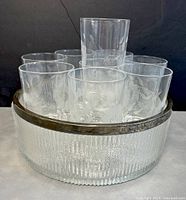 Front view of serving bowl with silver plated rim and 9 etched glasses arranged inside it, showing the texture of bowl and floral cornflower etched pattern on glasses.